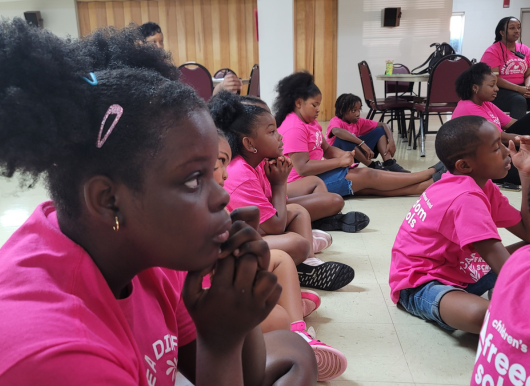 scholars sit during harambee. girl listens attentively